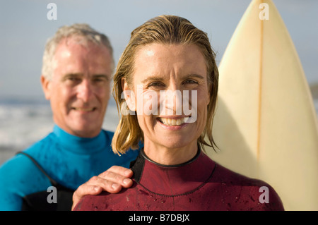 Couple wearing wetsuits on a beach Stock Photo