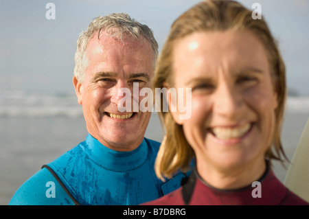 Couple wearing wetsuits on a beach Stock Photo