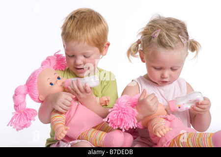 Two little girls feeding their dolls Stock Photo