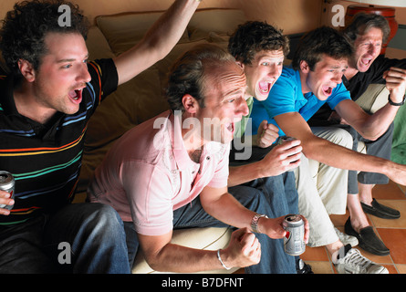 Men watching television, holding beers Stock Photo