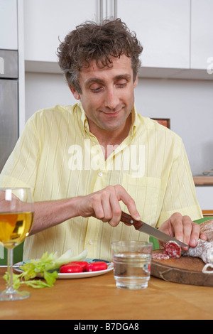 Man at home cutting salami Stock Photo