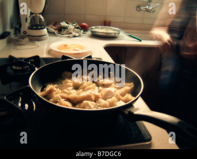 Woman preparing a home made Spanish Tortilla (aka Tortilla de patatas), Frying potatoes Stock Photo