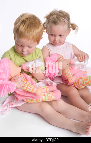 Two little girls feeding their dolls Stock Photo