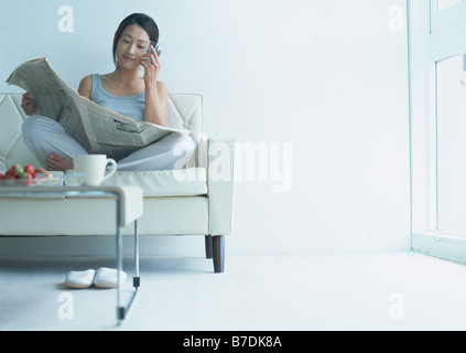 Woman reading newspaper on floor Stock Photo