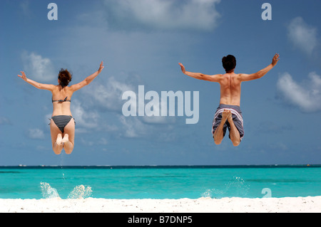 happy couple having fun on the beach jumping Stock Photo