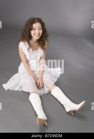 翻译结果： A woman in a white dress sitting on an outdoor folding chair ...
