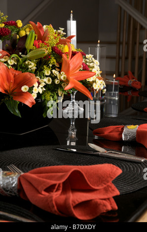 Autumn dinner table setting with red napkins and flowers on a black background Stock Photo