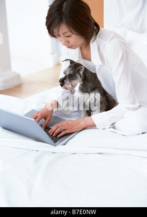 Woman using laptop on bed Stock Photo