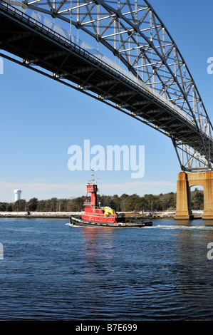 Red tugboat passing under Bourne Bridge in the Cape Cod Canal from Bouchard Transportation Company Stock Photo