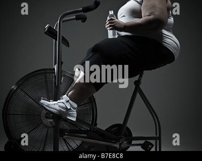 Overweight woman on exercise bike Stock Photo