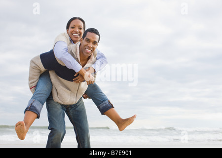 Man giving woman piggyback by the sea Stock Photo