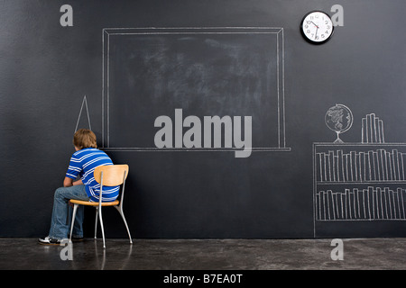 A boy sat in a corner with a chalk dunce cap Stock Photo