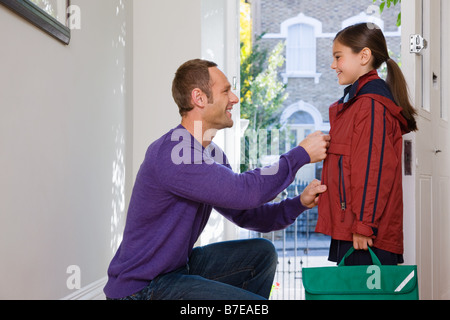 A father doing up his daughters coat Stock Photo