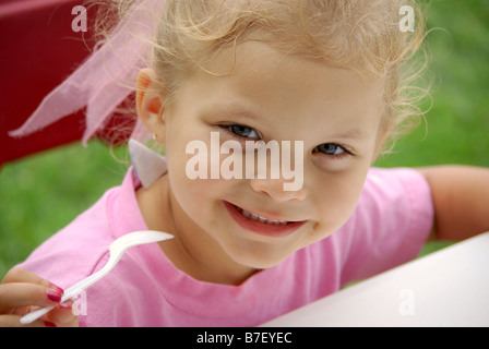 A biracial four year old girl eats a bowl of ice cream at a picnic. Stock Photo