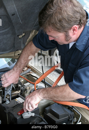 A mechanic using jumper cables to start a car battery Vertical Stock Photo