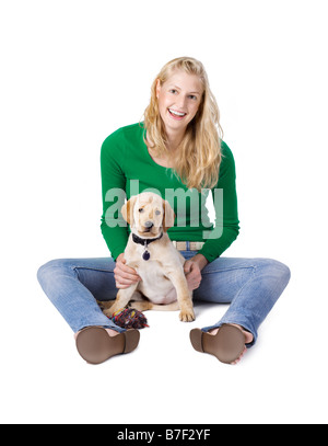 Blonde Girl sitting with a 9 week old Labrador cross Golden Retriever puppy on a white background Stock Photo