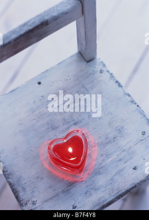 Heart-shaped candle on chair Stock Photo