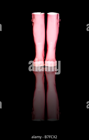A pair of pink wellies, or wellington boots against a black background with reflection added digitally Stock Photo