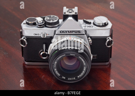 Olympus OM2n single lens reflex 35mm camera with 50mm f1 8 Zuiko lens darkwood background Stock Photo