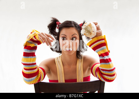 Beautiful Latina girl eating a cupcake with her fingers looking cross eyed isolated Stock Photo