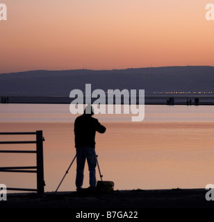 a photographer setting up his camera to take a shot of the sun setting over North Wales Stock Photo