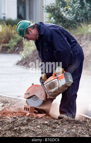 Workman using an Angle Grinder to cut a brick Stock Photo