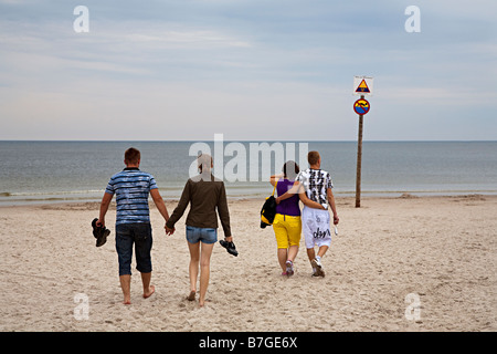 Two couples young peoplle walking hand in hand on beach at Baltic seaside resort of Leba Poland Stock Photo