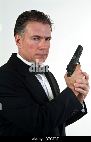 A man in formal attire holding an automatic pistol taken against a white background Stock Photo