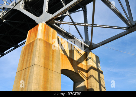 Looking up from under a bridge showing the concrete support steel girders and blue sky Stock Photo