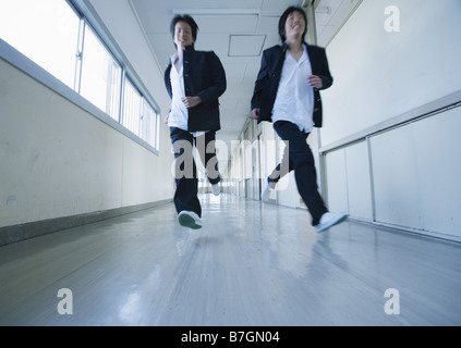 Two young schoolboys running in corridor Stock Photo