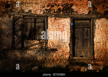 a Turkish degraded old weathered building with a wooden shuttered window and door in Kayakoy Turkey Stock Photo