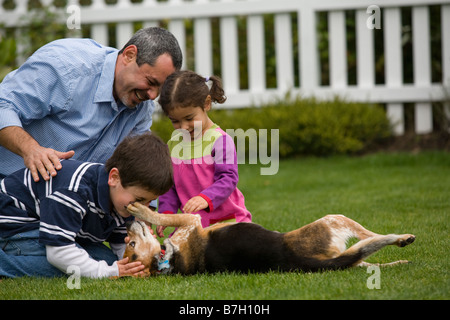 Family playing with dog in backyard Stock Photo