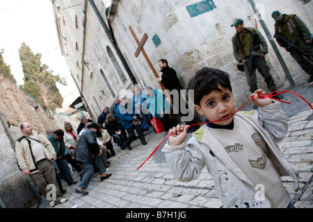 Christian pilgrims praying on the Via Dolorosa near a Palestinian child and Israeli police in the Old City of Jerusalem Stock Photo