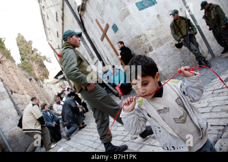 Christian pilgrims praying on the Via Dolorosa near a Palestinian child and Israeli police in the Old City of Jerusalem. Stock Photo