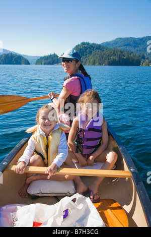 Mother and daughters rowing canoe on lake Stock Photo