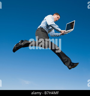 African businessman typing on laptop in mid-air Stock Photo