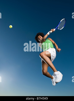 African woman playing tennis in mid-air Stock Photo