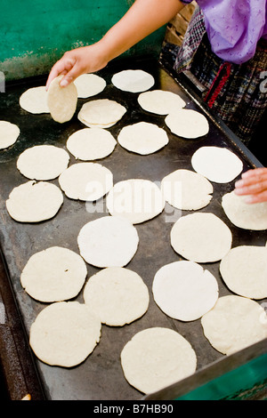 A Guatemalan woman prepares fresh tortillas on a hot stove in the market in Solola, Guatemala Stock Photo