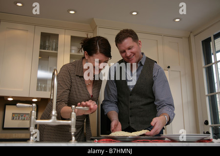 Couple preparing a fast-food pizza in their kitchen Stock Photo