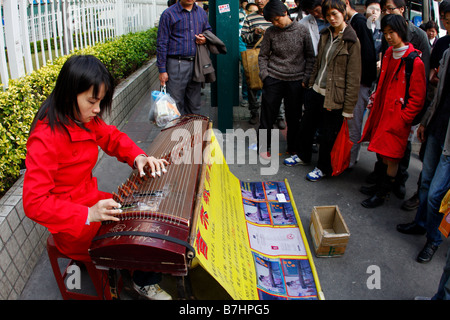 Teacher playing music on street in hopes to find private students as Chinese Economy worsens Stock Photo