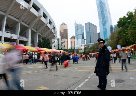 Police Man watching carefully as I photograph Guangzhou Flower Expo with office buildings and stadium in skyline Citic Plaza the Stock Photo