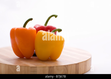 Yellow, orange and red peppers on butcher block cutting board in profile Stock Photo