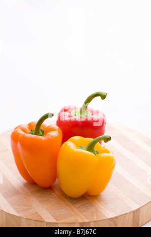 Yellow, orange and red peppers on butcher block cutting board Stock Photo