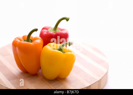 Yellow, orange and red peppers on butcher block cutting board Stock Photo