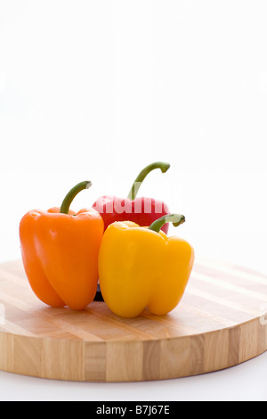 Yellow, orange and red peppers on butcher block cutting board Stock Photo