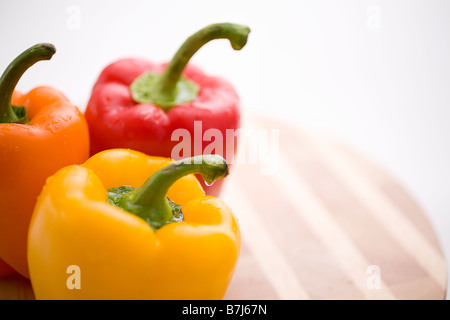 Yellow, orange and red peppers on butcher block cutting board Stock Photo