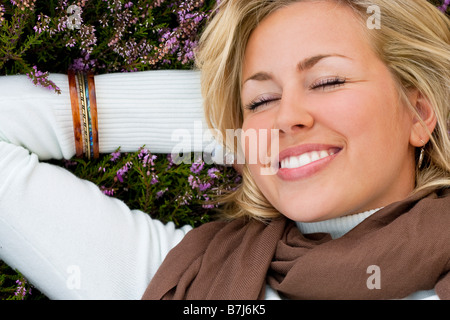 A beautiful blond haired blue eyed laying down and thinking happy thoughts in a field of heather Stock Photo