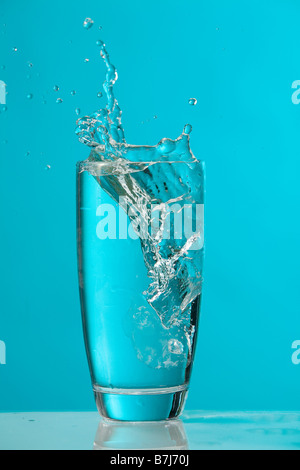 Water splash as ice cube drops into glass of water Stock Photo