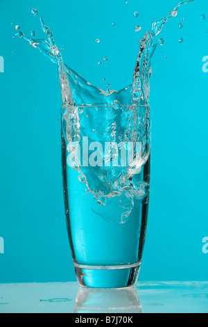 Water splash as ice cube drops into glass of water Stock Photo