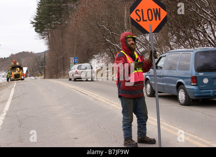 Flagger road worker holds traffic sign in middle of road Stock Photo